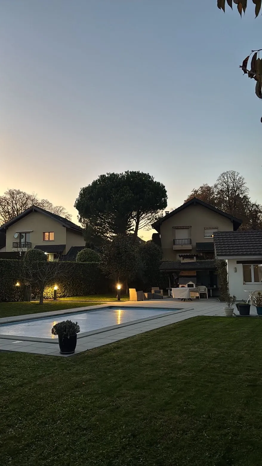 Jardin avec piscine et gazon entretenu au crépuscule
