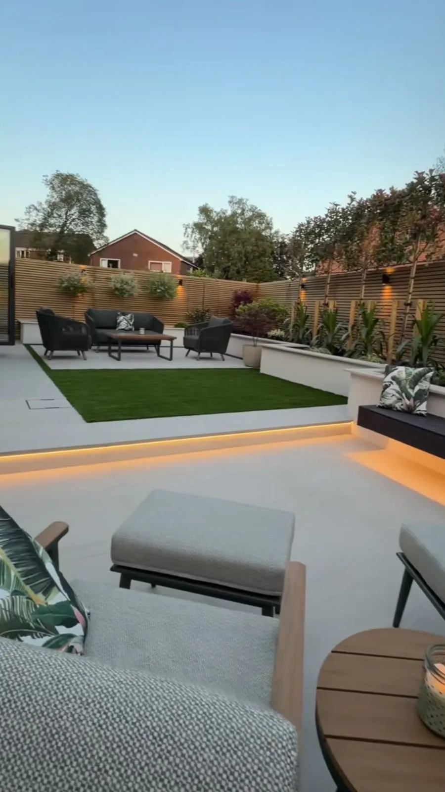 Jardin contemporain avec terrasse en dalles, gazon, bacs maçonnés et éclairage LED intégré