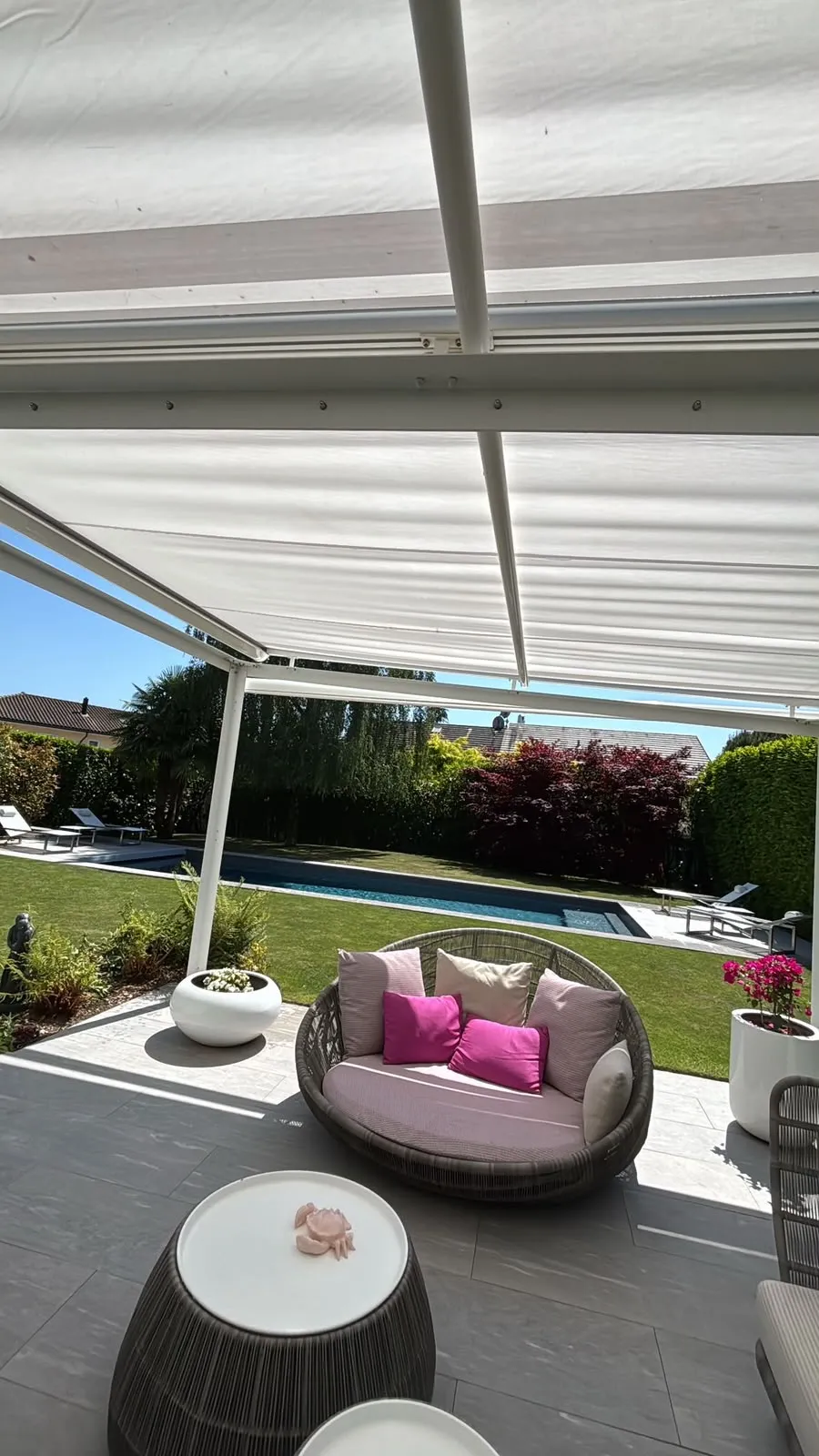 Terrasse sous pergola donnant sur un gazon et une piscine